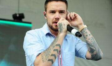 Liam Payne îmbrăcat într-o cămașă albastră în timp ce cântă la microfon