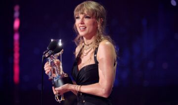 Taylor Swift îmbrăcată într-o rochie elegantă neagră, vorbind la microfon la MTV VMA 2023