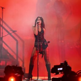 Dua Lipa îmbrăcată într-o ținută sexy neagră, cântând pe scenă