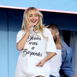 Sabrina Carpenter îmbrăcată cu un tricou alb, cântând la microfon